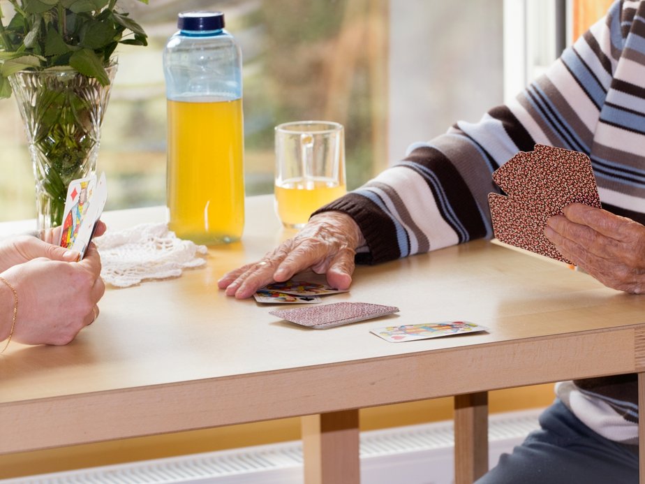 Bewohnerin und Betreuerin spielen Karten.